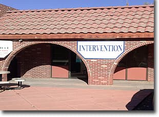 Brick storefront with arched openings and an Intervention sign under a red tile roof