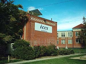 The brick ICCS Kendall building with an iccs sign, beside the two-story former hospital